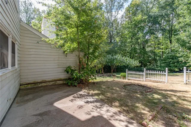 a backyard of a house with large trees and plants