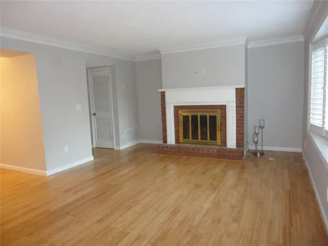 an empty room with wooden floor fireplace and windows