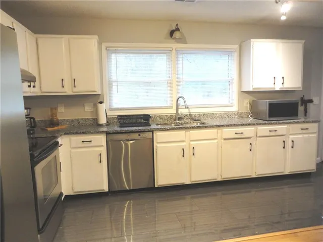 a kitchen with granite countertop white cabinets and white appliances