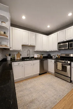 a kitchen with granite countertop a stove top oven sink and cabinets