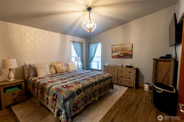 a bedroom with bed tv and wooden floor