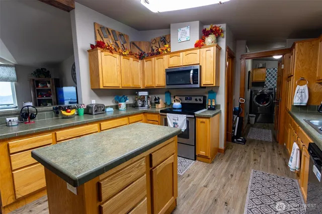 a kitchen with stainless steel appliances granite countertop a stove top oven a sink dishwasher a dining table and chairs with wooden floor