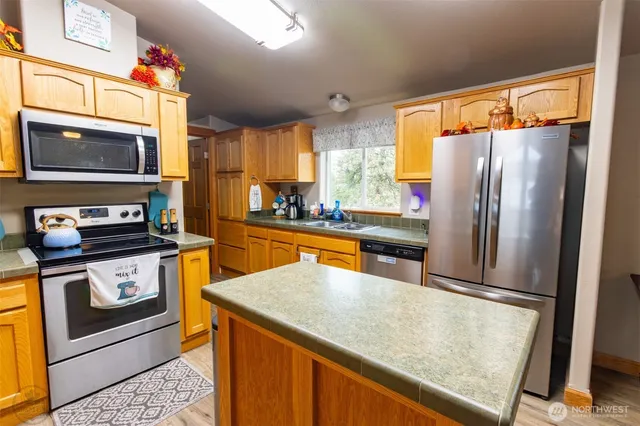 a kitchen with stainless steel appliances granite countertop a refrigerator a stove top oven a sink and dishwasher