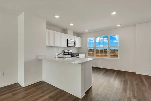 a kitchen with stainless steel appliances granite countertop a sink a stove a refrigerator cabinets and a wooden floor