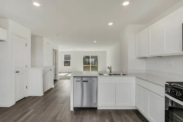 a kitchen with granite countertop a sink and dishwasher a stove top oven with wooden floor