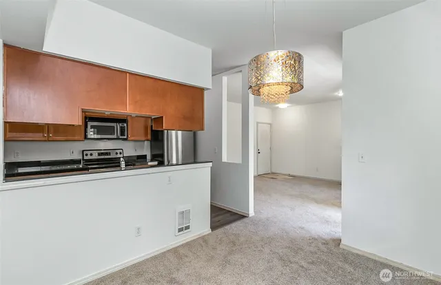 a view of kitchen with stainless steel appliances wooden floor and chair