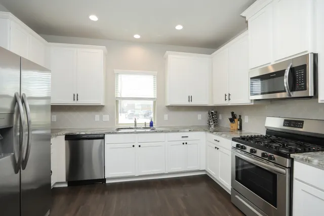 a kitchen with stainless steel appliances granite countertop a stove a sink and a refrigerator