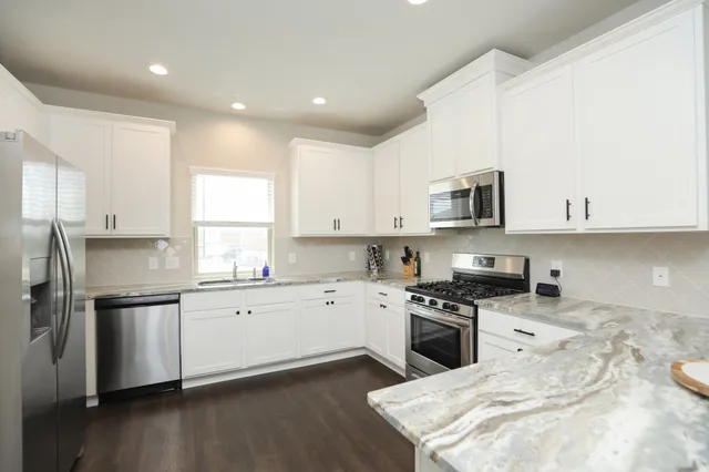 a kitchen with granite countertop white cabinets and stainless steel appliances