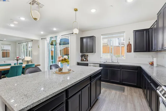 a kitchen with granite countertop a sink a counter space appliances and cabinets
