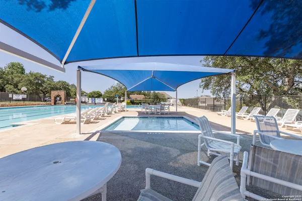 a small pool with lawn chairs under an umbrella