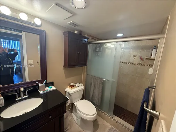 a bathroom with a granite countertop toilet sink and mirror