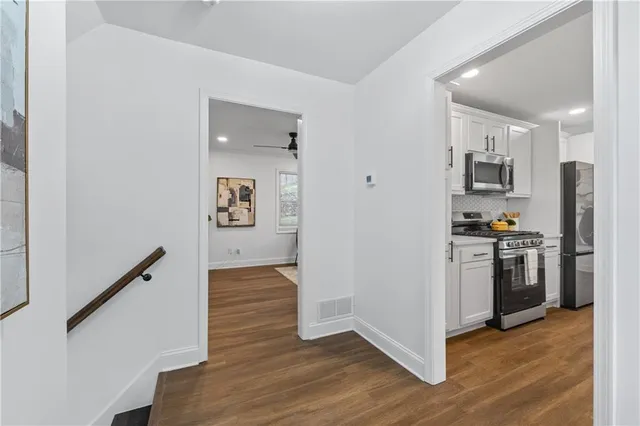a kitchen with a refrigerator a stove top oven and wooden floor