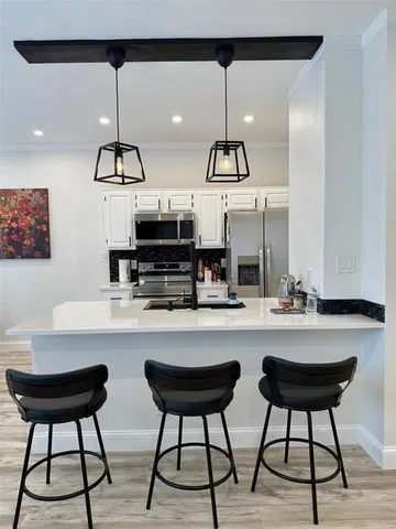 a kitchen with stainless steel appliances a table chairs and white cabinets