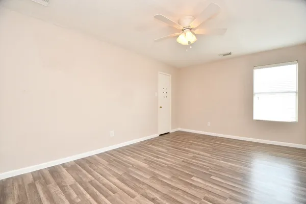 an empty room with wooden floor and windows