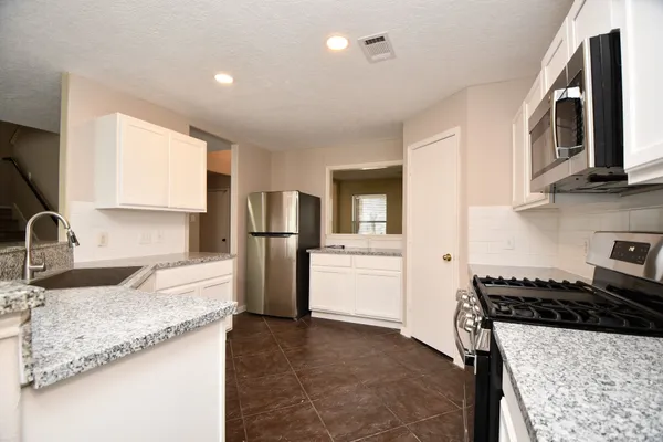 a kitchen with stainless steel appliances granite countertop a sink stove and refrigerator