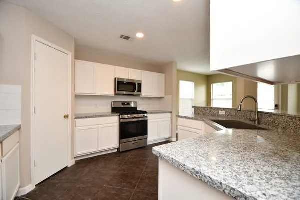 a large kitchen with stainless steel appliances granite countertop a sink and a stove