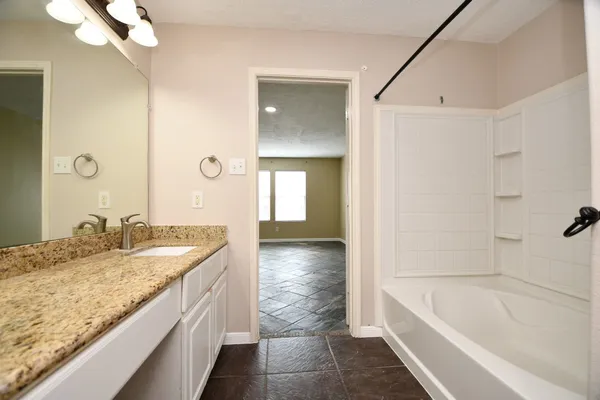 a bathroom with a granite countertop sink mirror and a bath tub