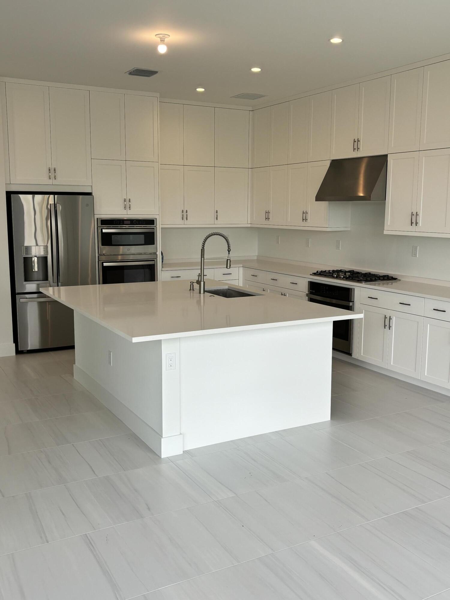 a kitchen with stainless steel appliances granite countertop a sink a stove and a refrigerator