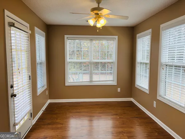 a view of an empty room with a window and wooden floor