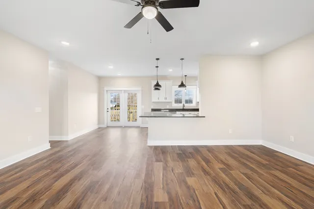 a view of an empty room with a window and wooden floor