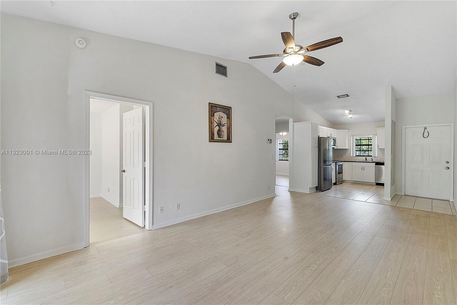 3000 Norwood Place, Unit N202 Boca Raton, FL 33431 - Photo 11 of 26 a view of an empty room with a ceiling fan and kitchen view