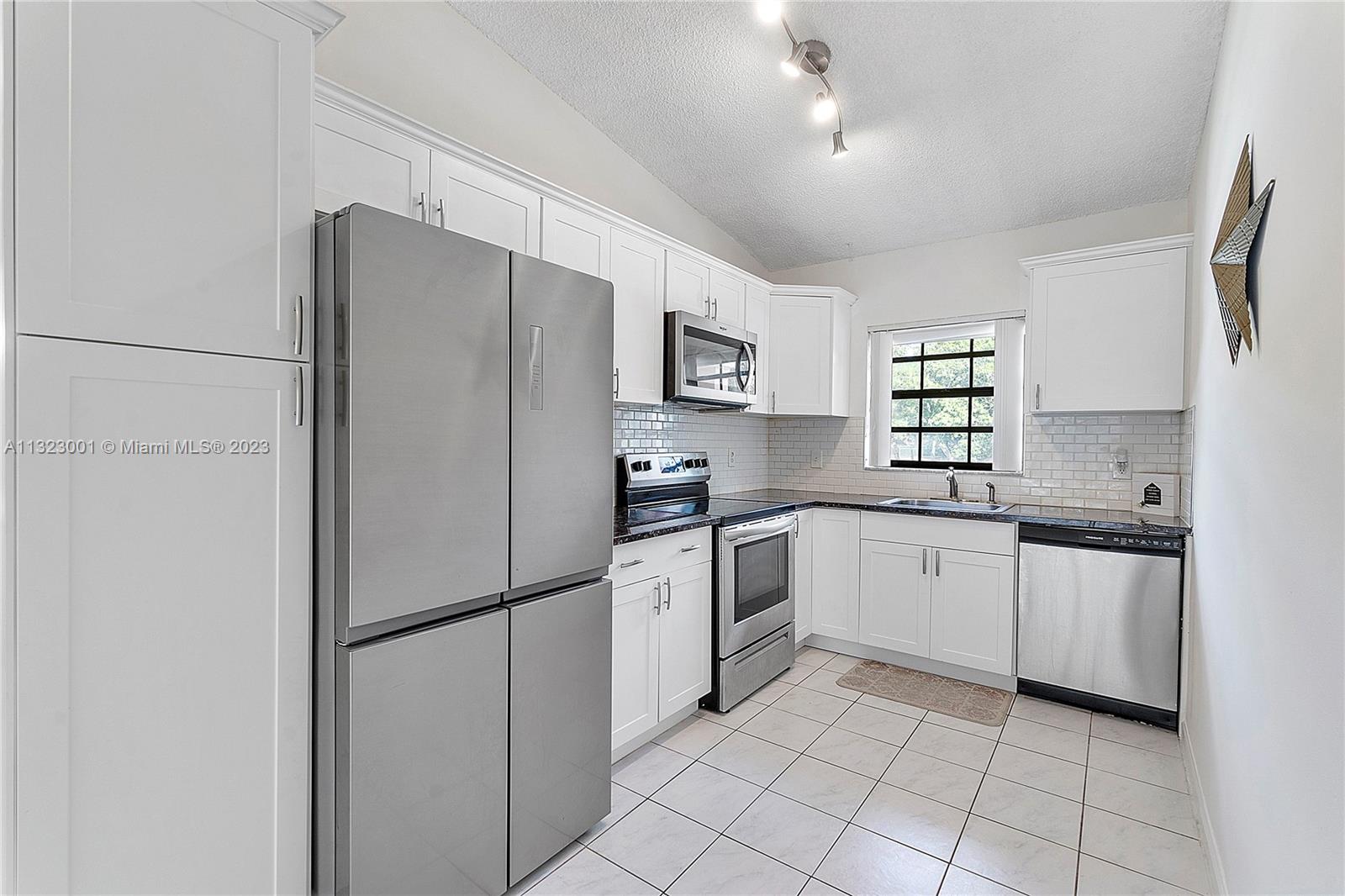 3000 Norwood Place, Unit N202 Boca Raton, FL 33431 - Photo 13 of 26 a kitchen with stainless steel appliances a refrigerator sink and microwave