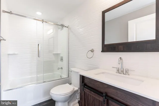 a bathroom with a shower sink vanity mirror and toilet