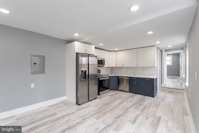a large kitchen with stainless steel appliances kitchen island a large counter top and wooden floor
