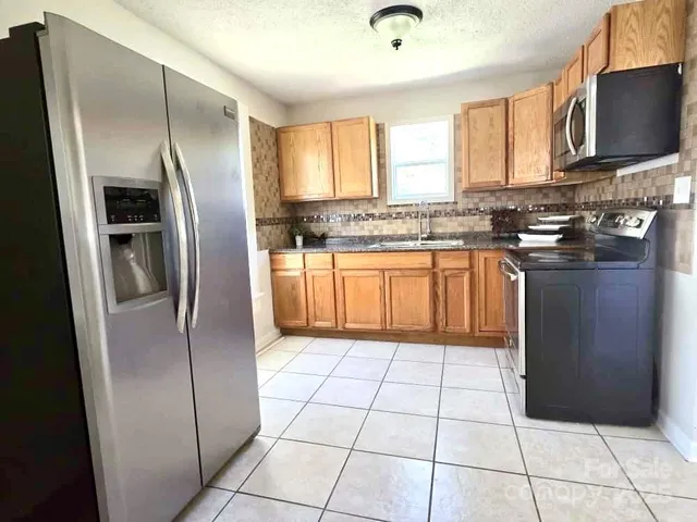 a kitchen with stainless steel appliances granite countertop a refrigerator a sink a stove and cabinets