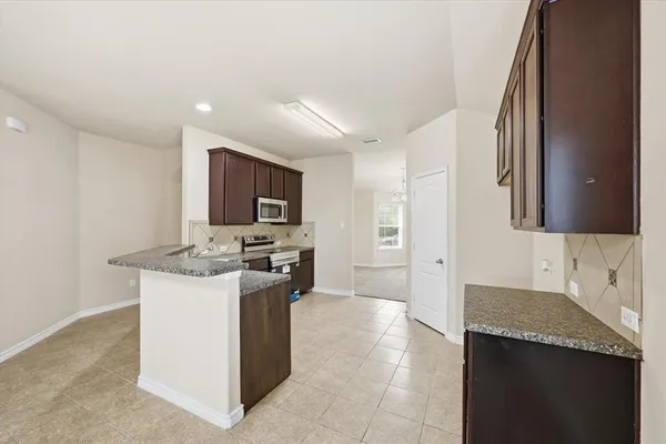 a large kitchen with stainless steel appliances granite countertop a stove top oven a sink dishwasher a dining table and chairs