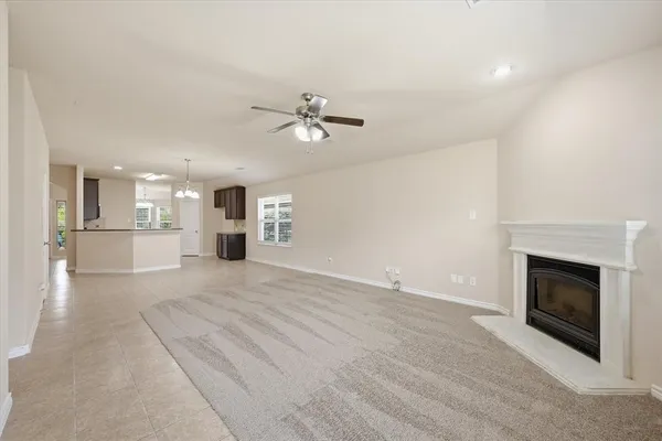 a view of a livingroom with a fireplace a chandelier fan and windows