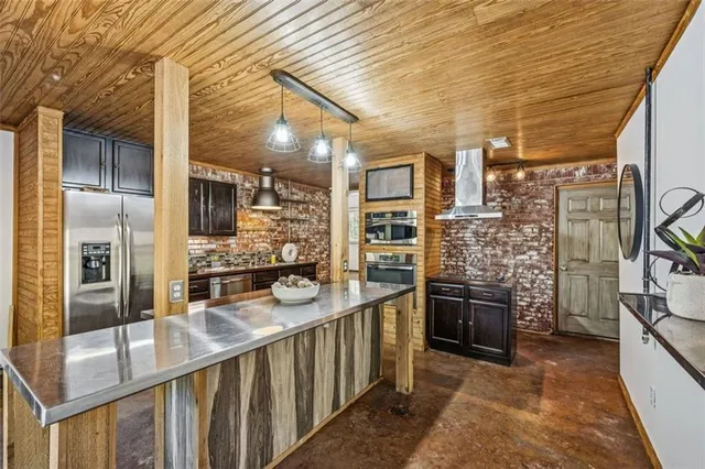 a kitchen with stainless steel appliances kitchen island granite countertop a stove and a wooden cabinets