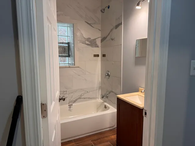 a bathroom with a tub shower vanity and a sink