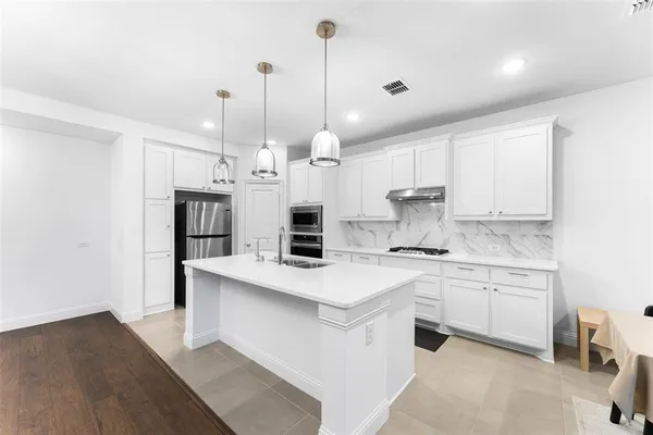 a kitchen with kitchen island a sink stainless steel appliances and cabinets