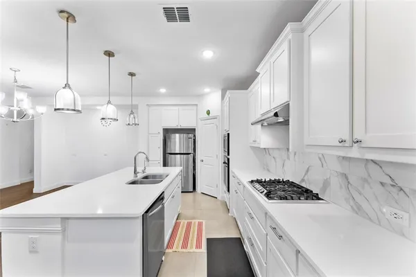 a kitchen with kitchen island a stove a sink a refrigerator and white cabinets with wooden floor