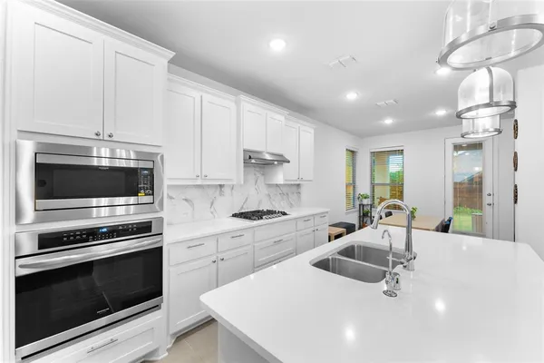 a kitchen with a sink stainless steel appliances and white cabinets