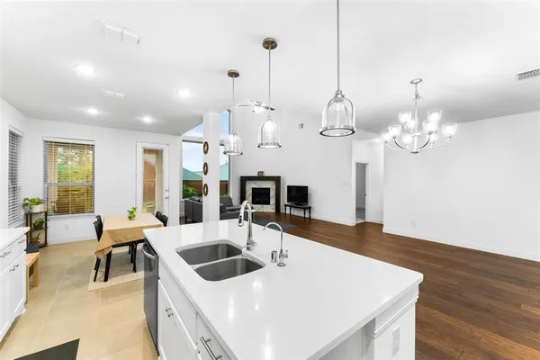a kitchen with a sink a chandelier and wooden floor