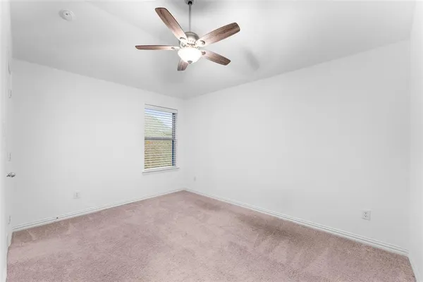 an empty room with a window and ceiling fan