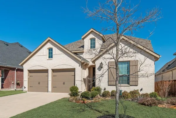 a view of a white house next to a yard with potted plants