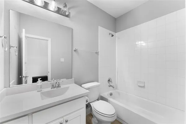 a bathroom with a toilet a sink a mirror a bathtub and vanity