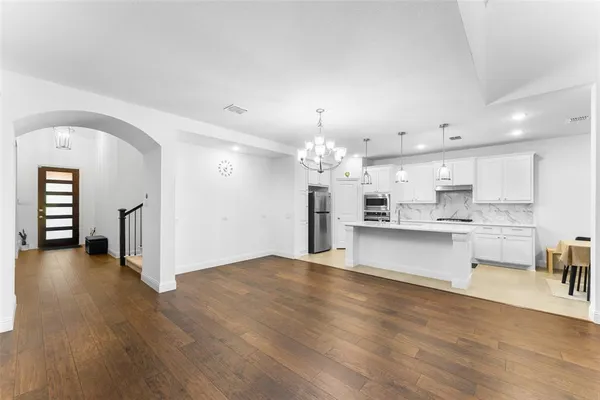 a view of a kitchen with a sink dishwasher a stove and kitchen island with wooden floor