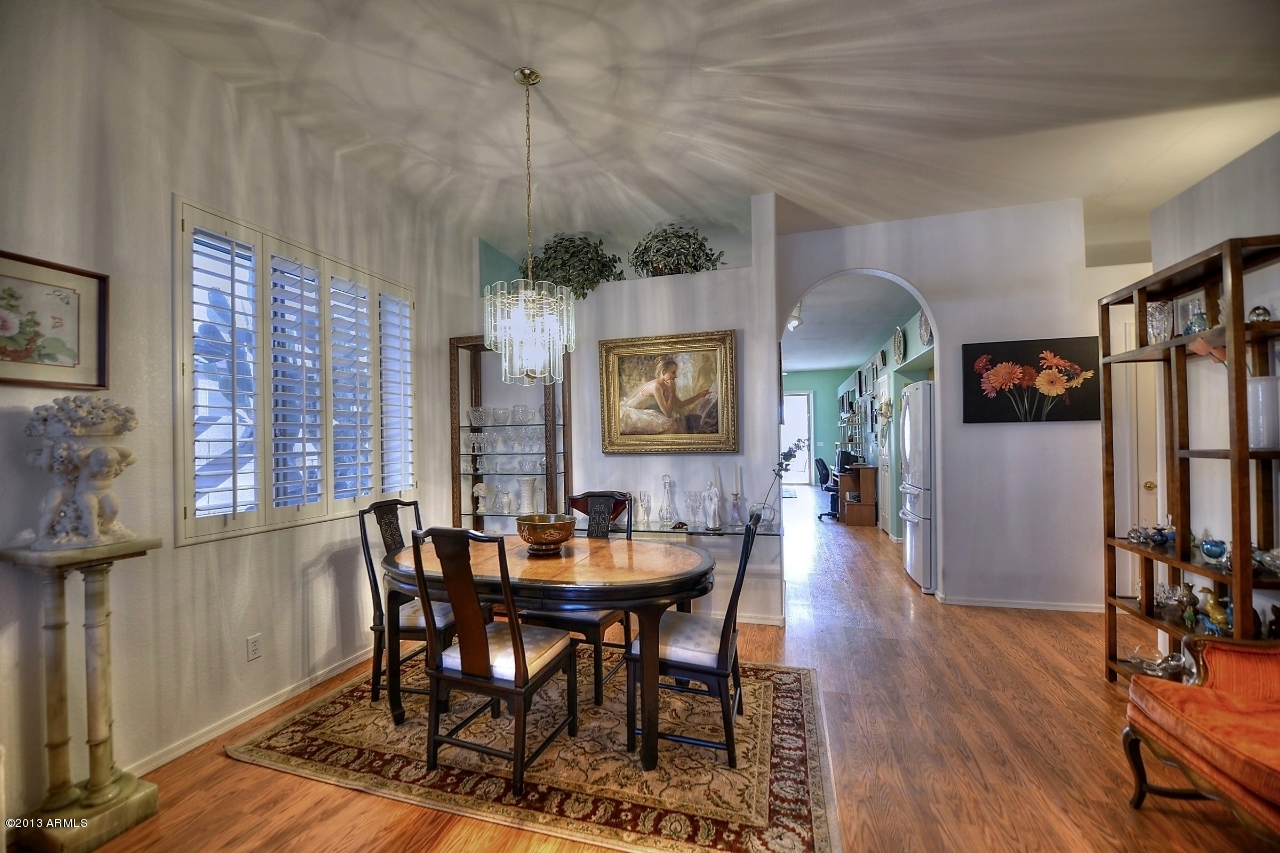 4243 East Tether Trail Phoenix, AZ 85050 - Photo 9 of 28 a dining room with wooden floor a chandelier a wooden table and chairs