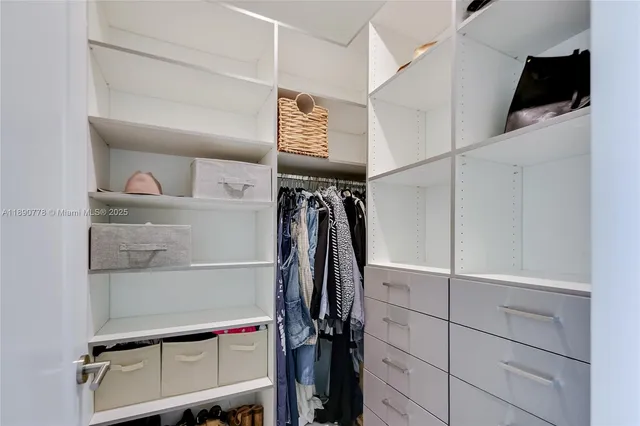 a view of walk in closet with clothes and shoes