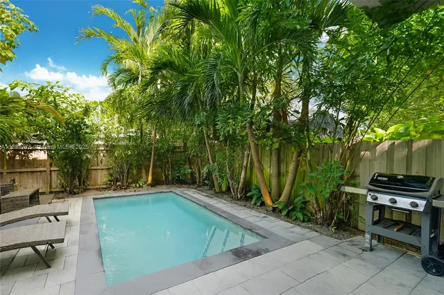 a view of a backyard with swimming pool and sitting area