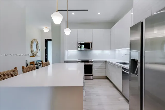 a large kitchen with a large counter top space a sink stainless steel appliances and cabinets