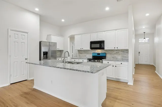 a kitchen with stainless steel appliances granite countertop a sink a stove a microwave and cabinets