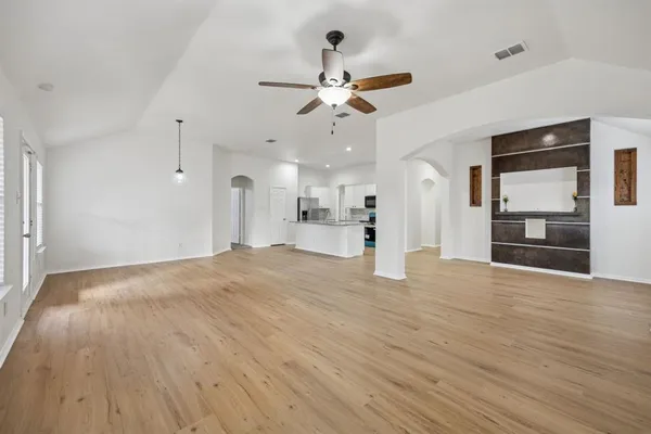 a view of an empty room with wooden floor and a window