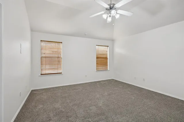 a view of empty room with wooden floor and ceiling fan