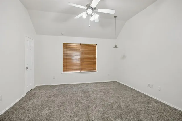an empty room with a window and ceiling fan