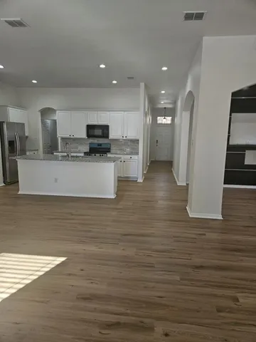 a view of kitchen with stainless steel appliances granite countertop a stove top oven a sink and a refrigerator